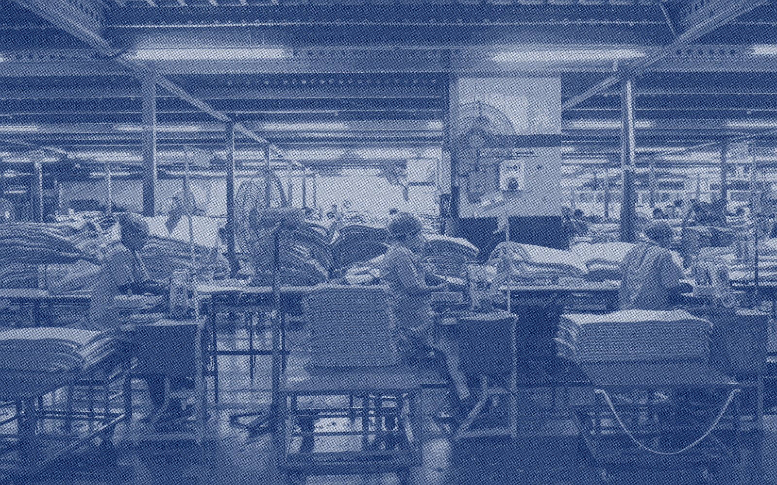 A production hall with rows of workstations and stacked material on trolleys