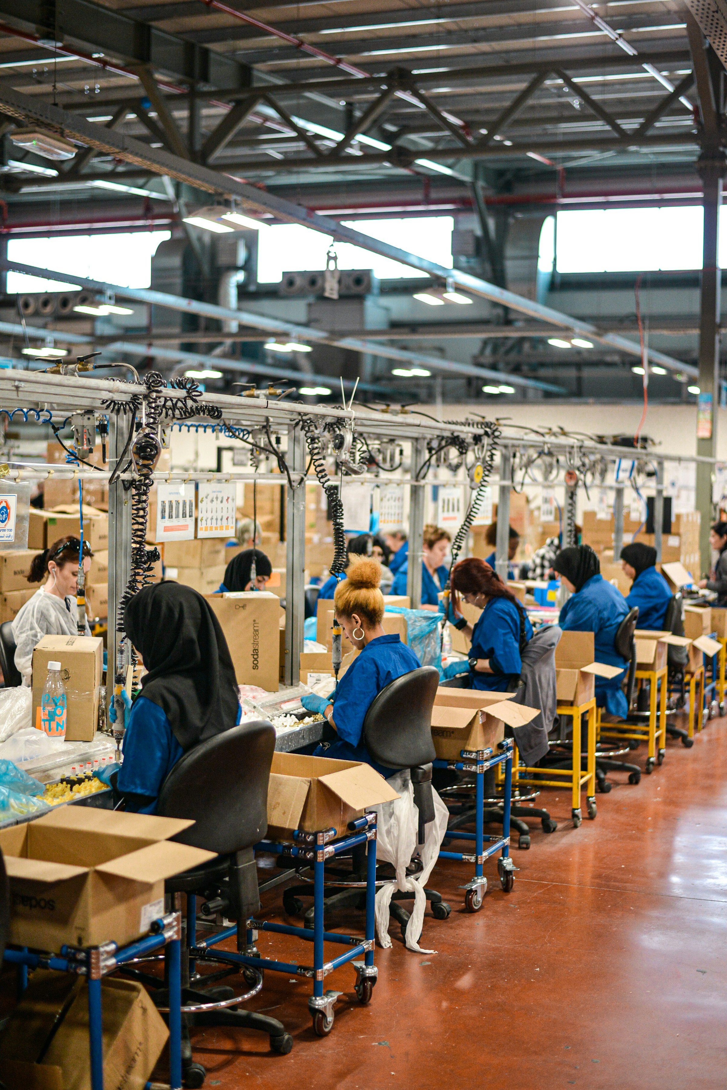 Workers at assembly benches along a production line in a factory hall