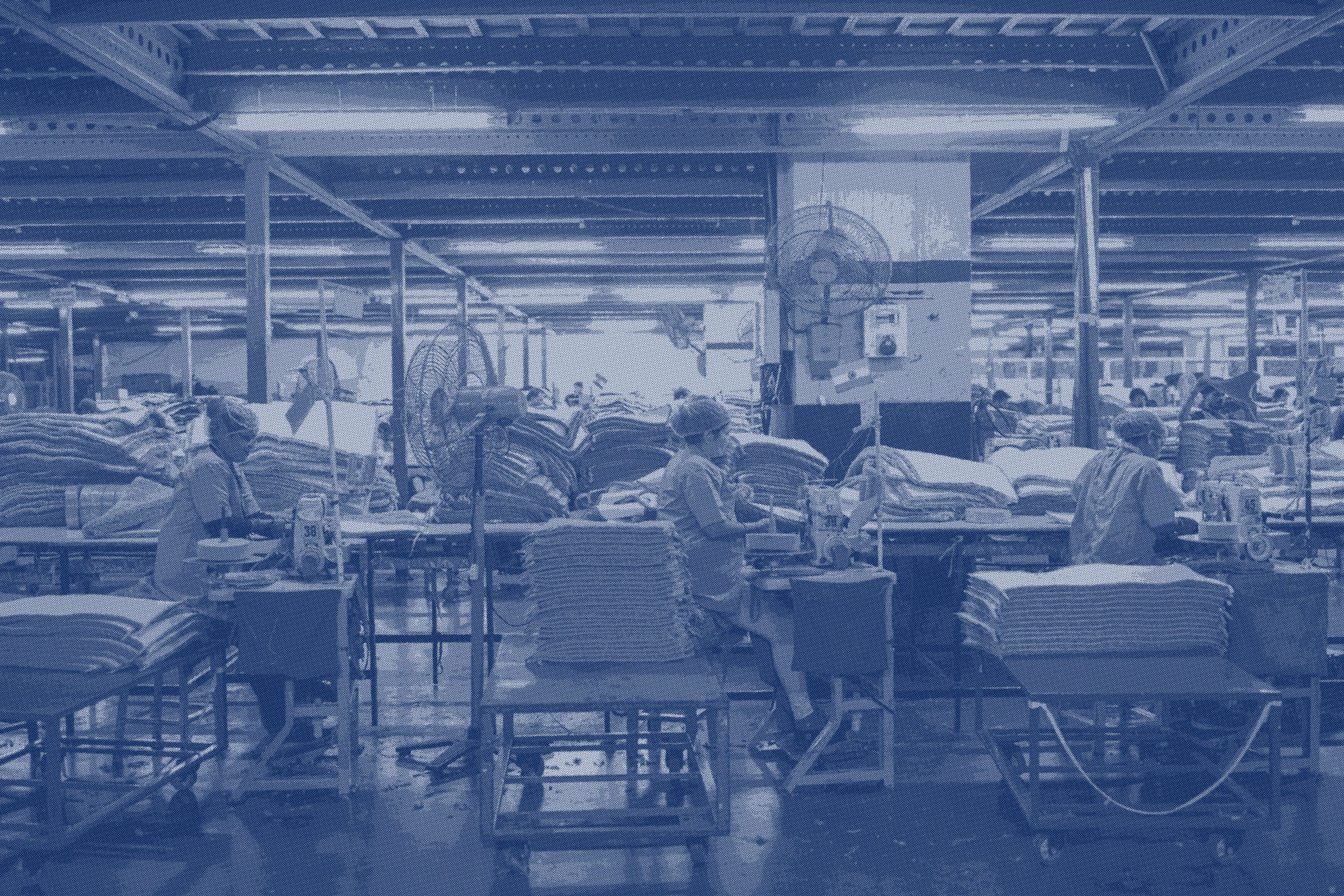 A production hall seen down a row of workstations, material stacked on both sides
